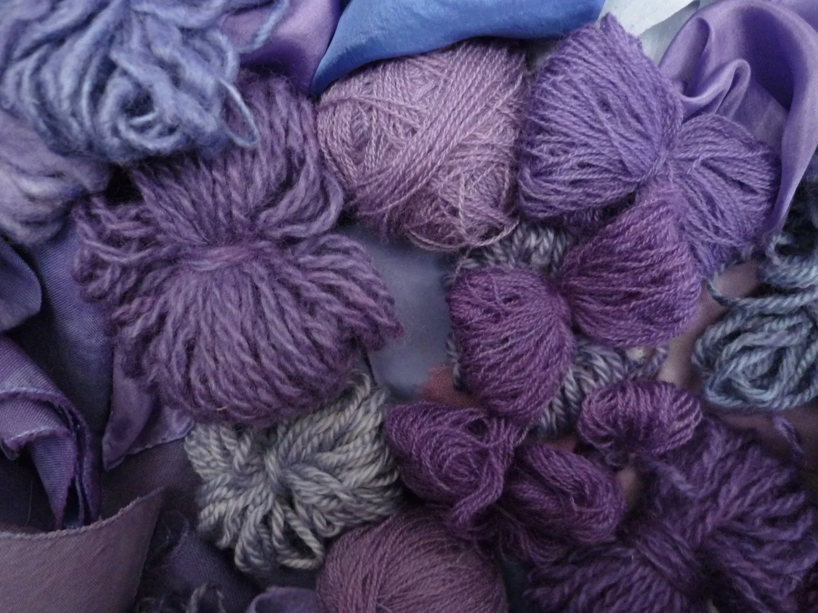 Skeins of wool yarn and folded cloth in shades from reddish purple to blue-violet, described as dyed with real purple, 2010