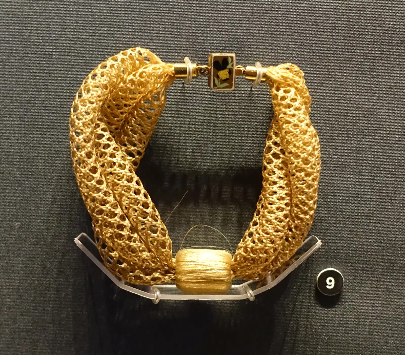 Bracelet of two open, hollow blond braids twisted together, enamel clasp; hair, clasp dated 1863, per its Commons file page