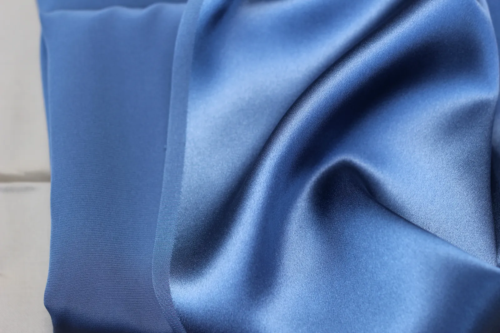 Blue cloth folded to show a shiny face at right and a dull, matte back at left