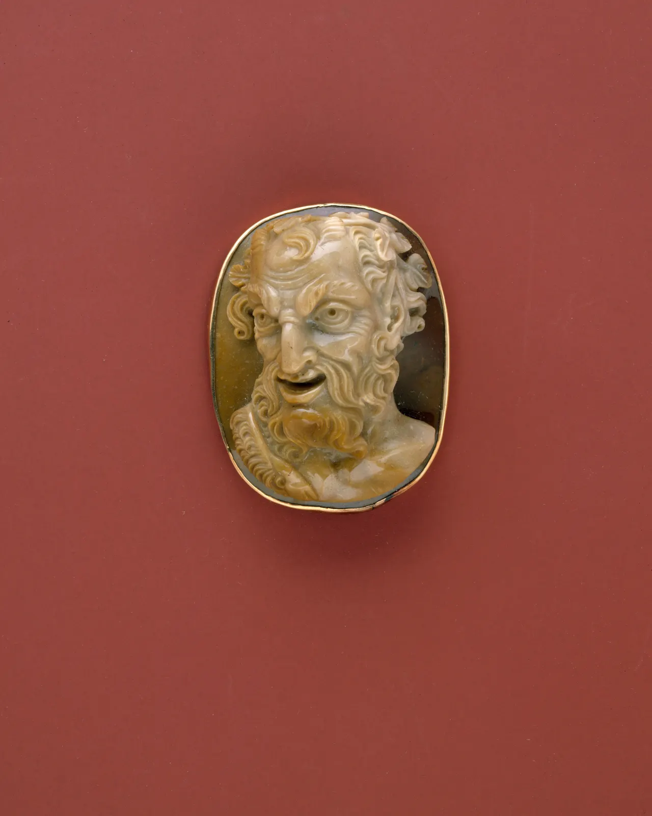 Bearded satyr head in high relief, pale on a dark ground, in a gold rim; late 18th or early 19th century; The Met 1982.60.392